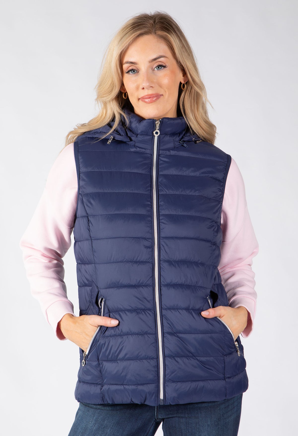 Model wearing a padded hooded gilet featuring a detachable hood. Secure zip pockets and zip up closure.