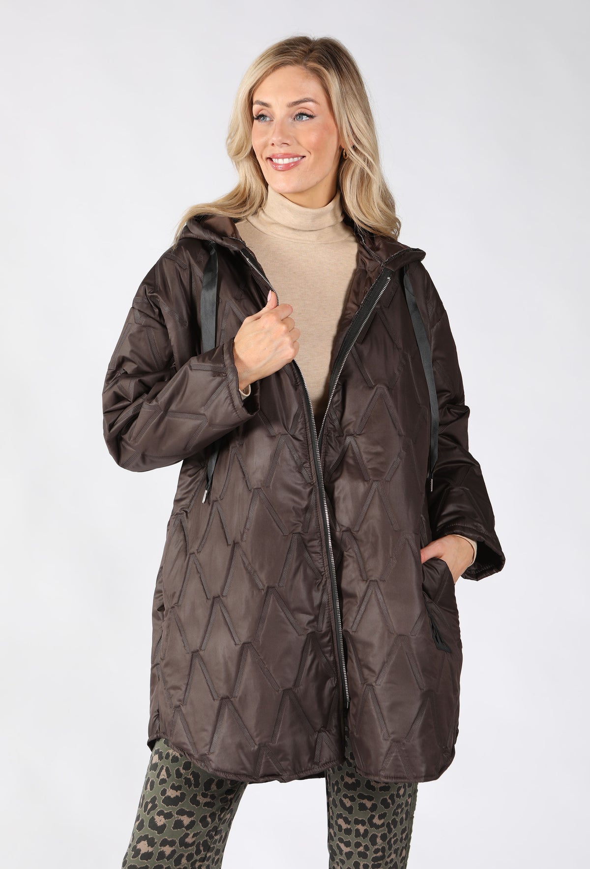 A woman modeling a dark brown quilted hooded puffer jacket with black drawstrings.