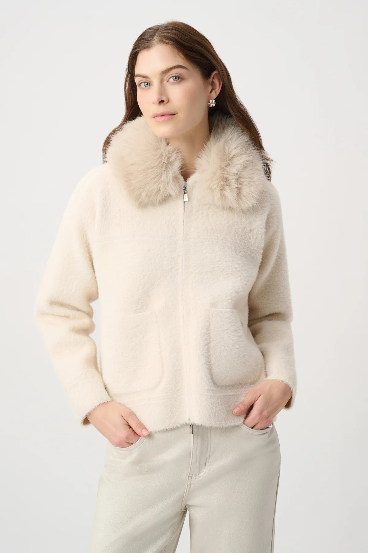 Woman wearing a cream-colored jacket with fur collar.