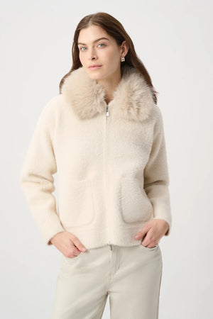 Woman wearing a cream-colored jacket with fur collar.