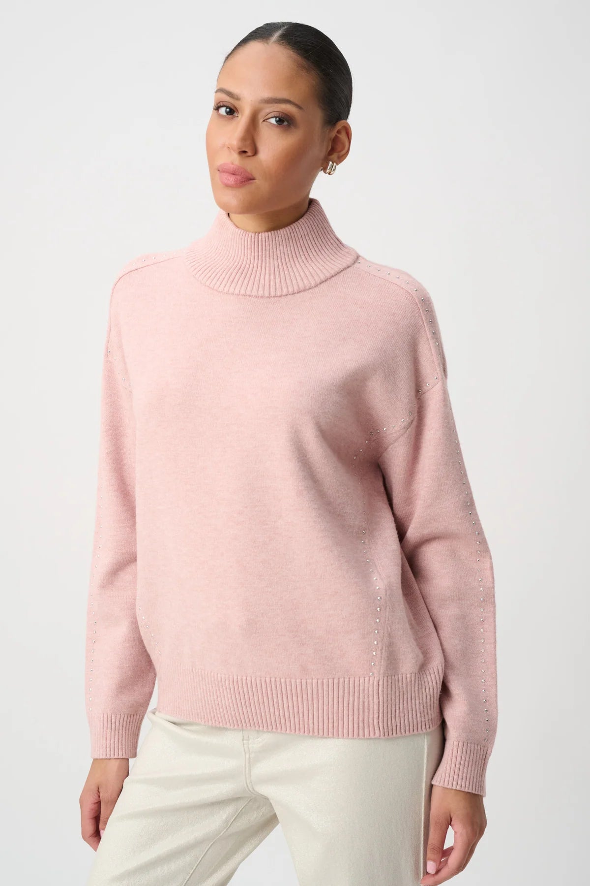 light pink knit mock-neck sweater and subtle silver bead detailing on the shoulders.