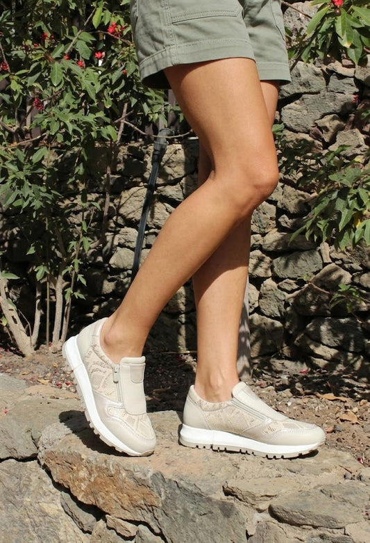 Person wearing light-colored sneakers on a stone path with greenery in the background