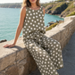 Woman in a polka dot outfit sitting by a scenic coastal view.
