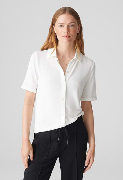 Woman wearing a white blouse and black pants on a gray background