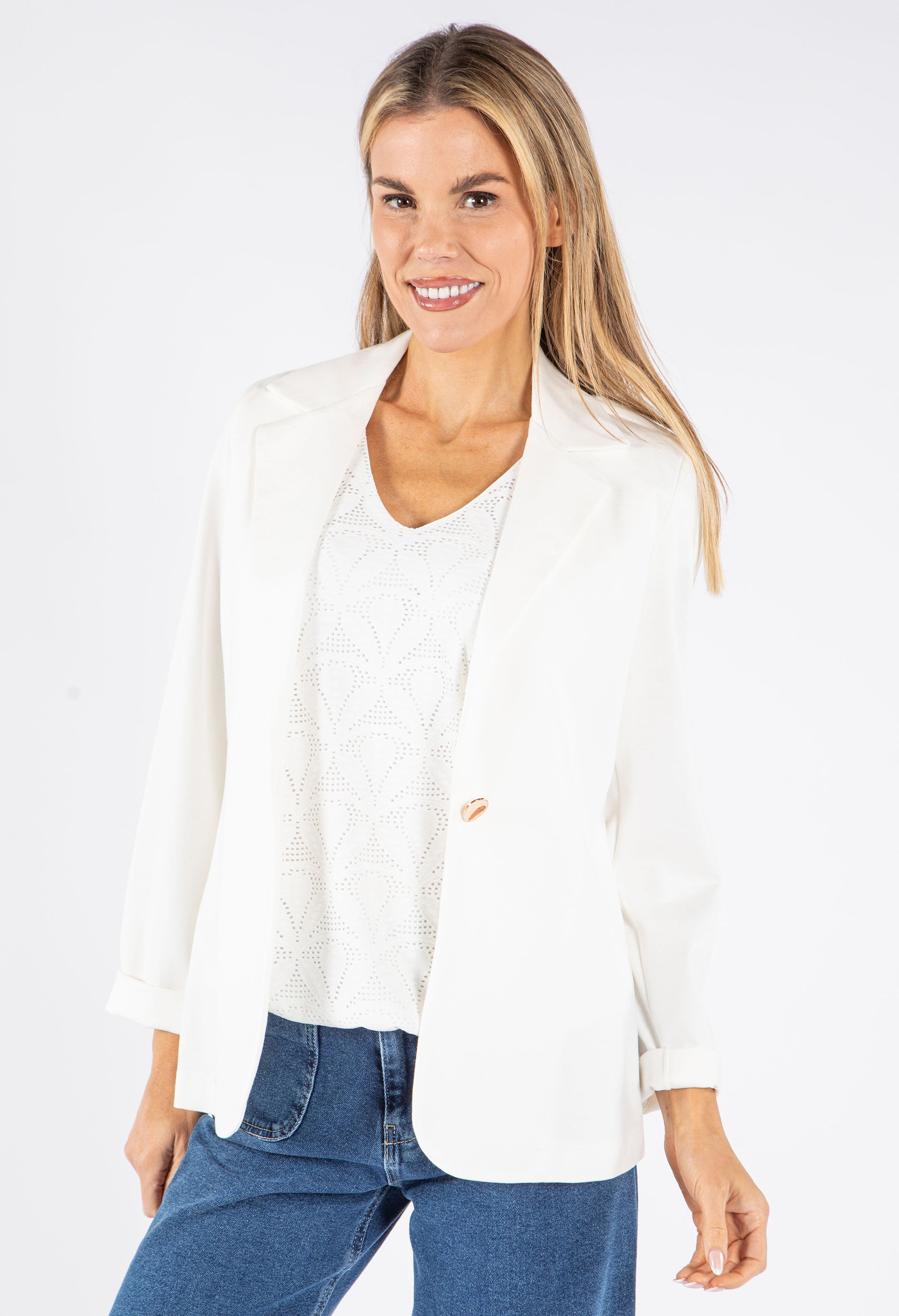 Woman wearing a white blazer and blue jeans on a white background