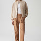 Woman wearing a beige jacket and brown pants on a white background