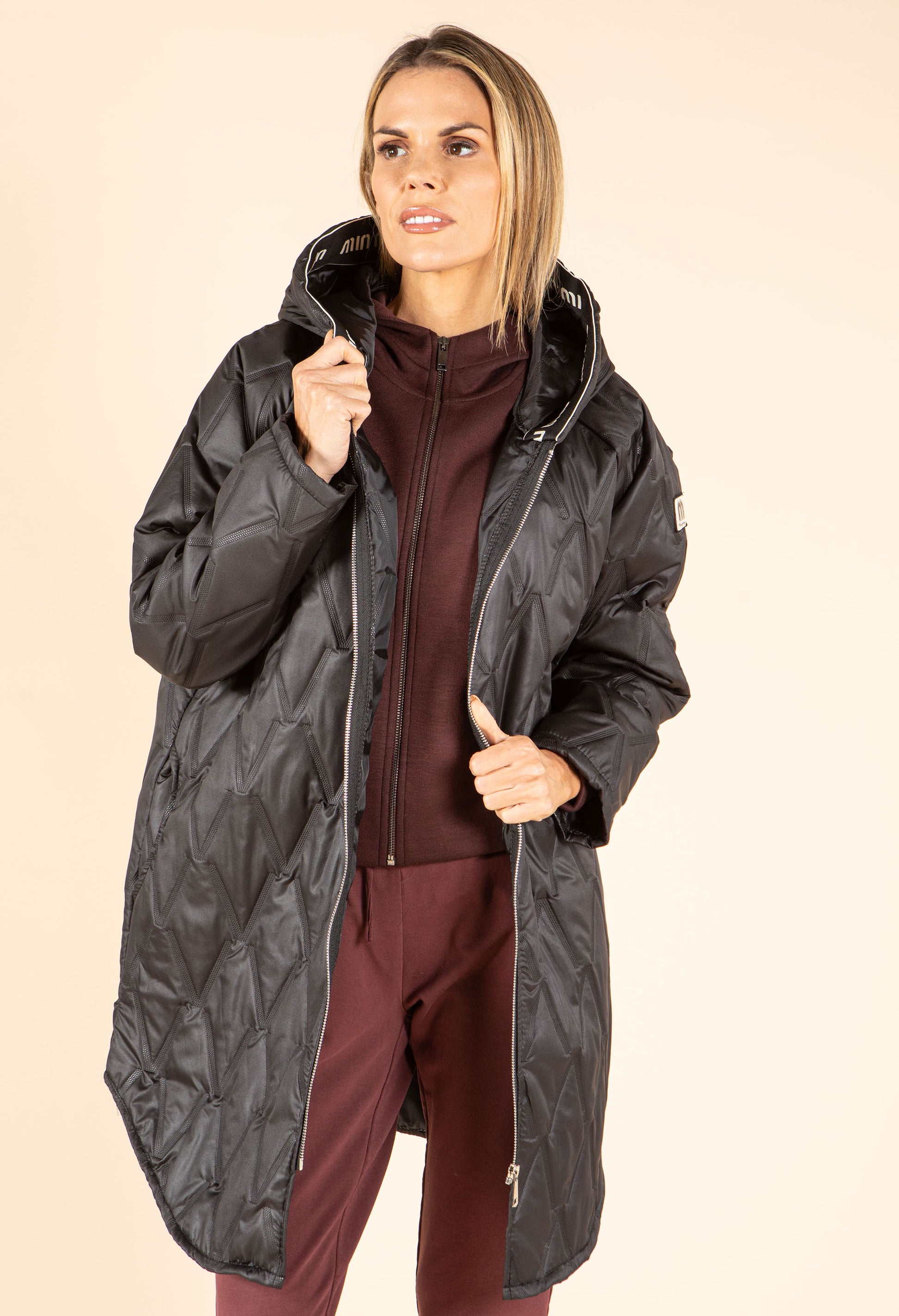 Woman wearing a black coat on a beige background