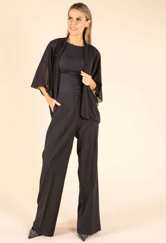 Woman wearing a black outfit with a patterned cardigan on a beige background