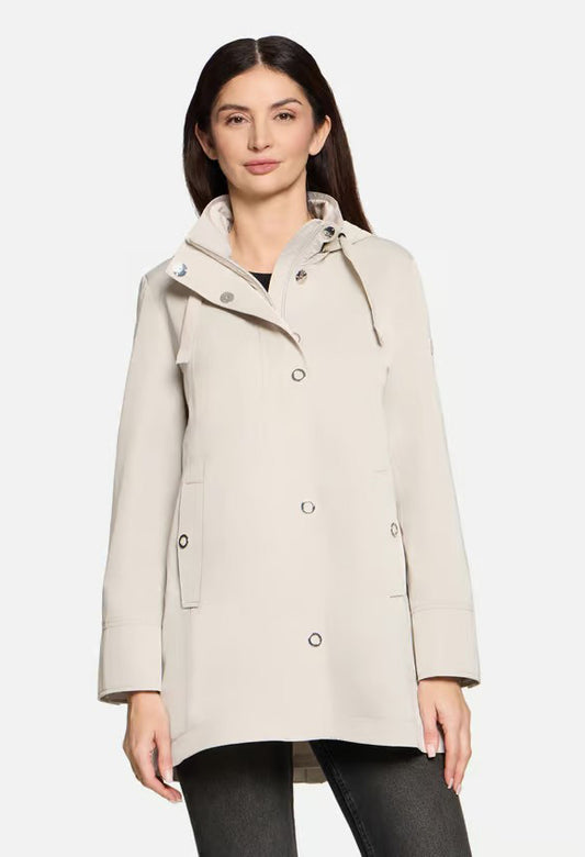 Woman wearing a navy coat, black top, and dark pants on a white background