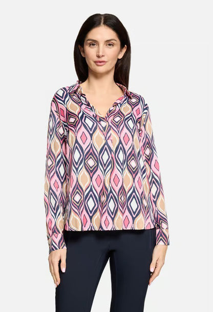 Woman wearing a patterned blouse with a plain background