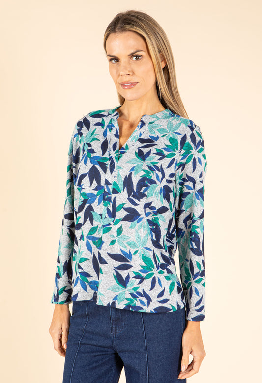 Woman wearing a long-sleeve shirt with a blue and green leaf pattern on a beige background
