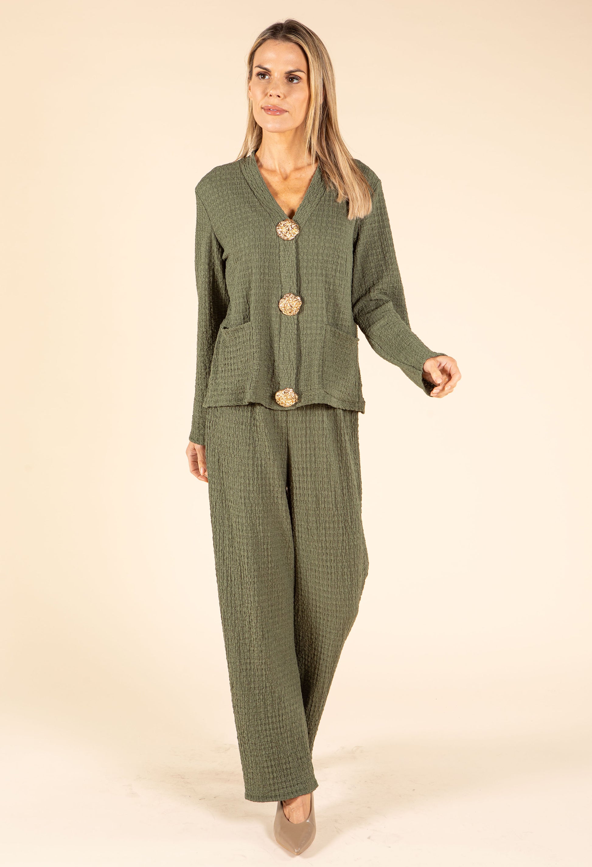 Woman wearing a green checkered outfit with buttons on a beige background