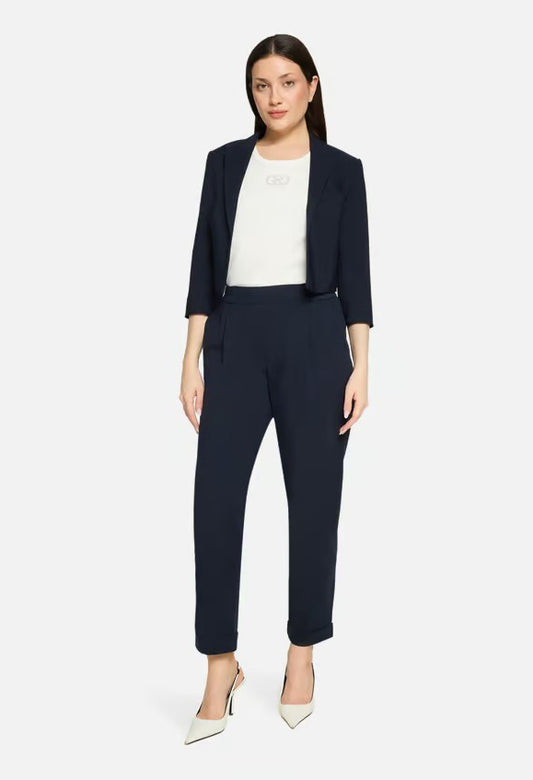 Woman wearing a navy suit with a white top on a light gray background