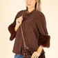 Woman wearing a brown coat with fur cuffs holding a leopard print bag on a beige background