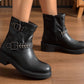 Black leather boots with buckles on a wooden floor