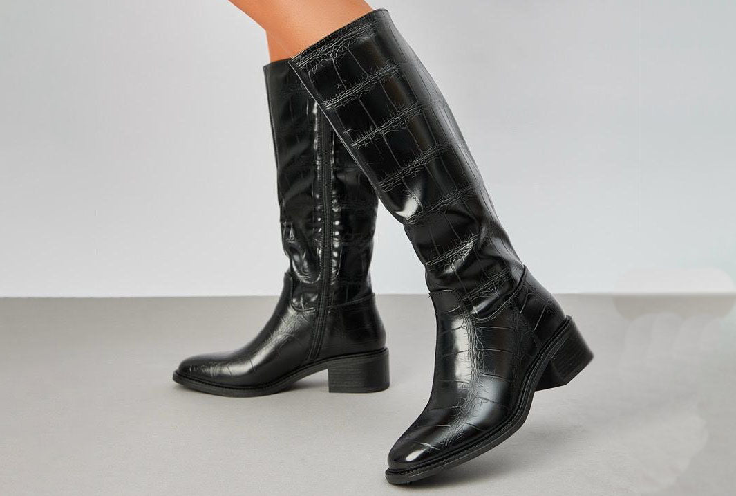 croc effect knee high boot with block heel on a grey background