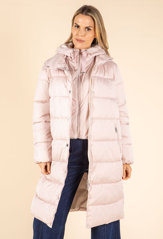 Woman wearing a long pink puffer coat against a beige background