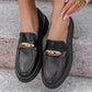 Black loafers with gold accents worn by a person on a stone surface