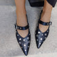 Black studded shoes worn on a concrete surface