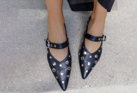 Black studded shoes worn on a concrete surface