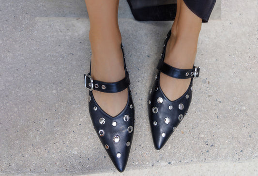 Black studded shoes worn on a concrete surface