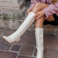 Person wearing white knee-high boots sitting on stone steps.