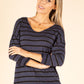Woman wearing a navy and white striped sweater against a beige background