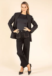 Woman wearing a black blazer and pants on a beige background