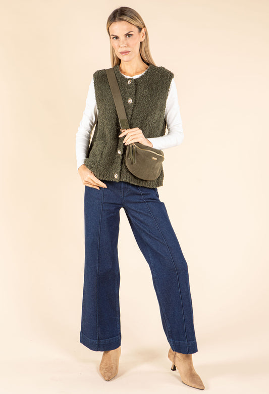 Woman wearing a beige knitted vest over a white shirt on a beige background