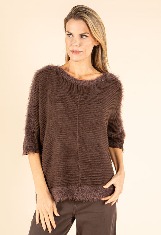 Woman wearing a brown knit sweater with a beige background