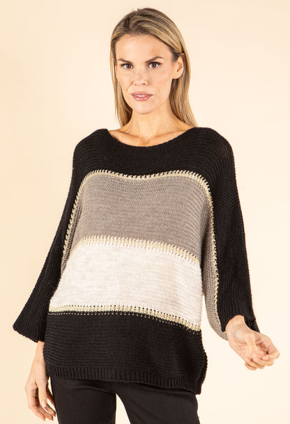 Woman wearing a black, gray, and beige striped sweater on a beige background