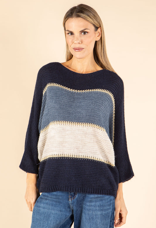 Woman wearing a black, gray, and beige striped sweater on a beige background