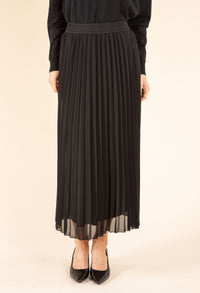 Person wearing a black pleated skirt on a beige background