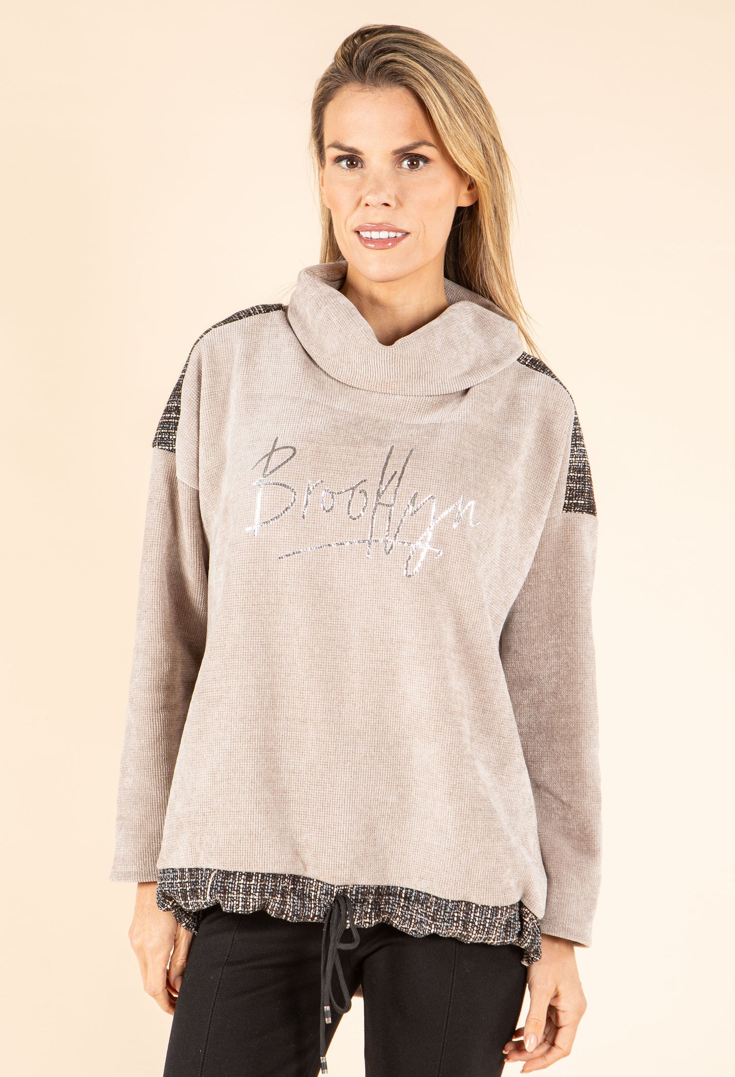 Woman wearing a gray sweater with 'Brooklyn' text on a beige background