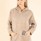 Woman wearing a beige hoodie with text on a beige background