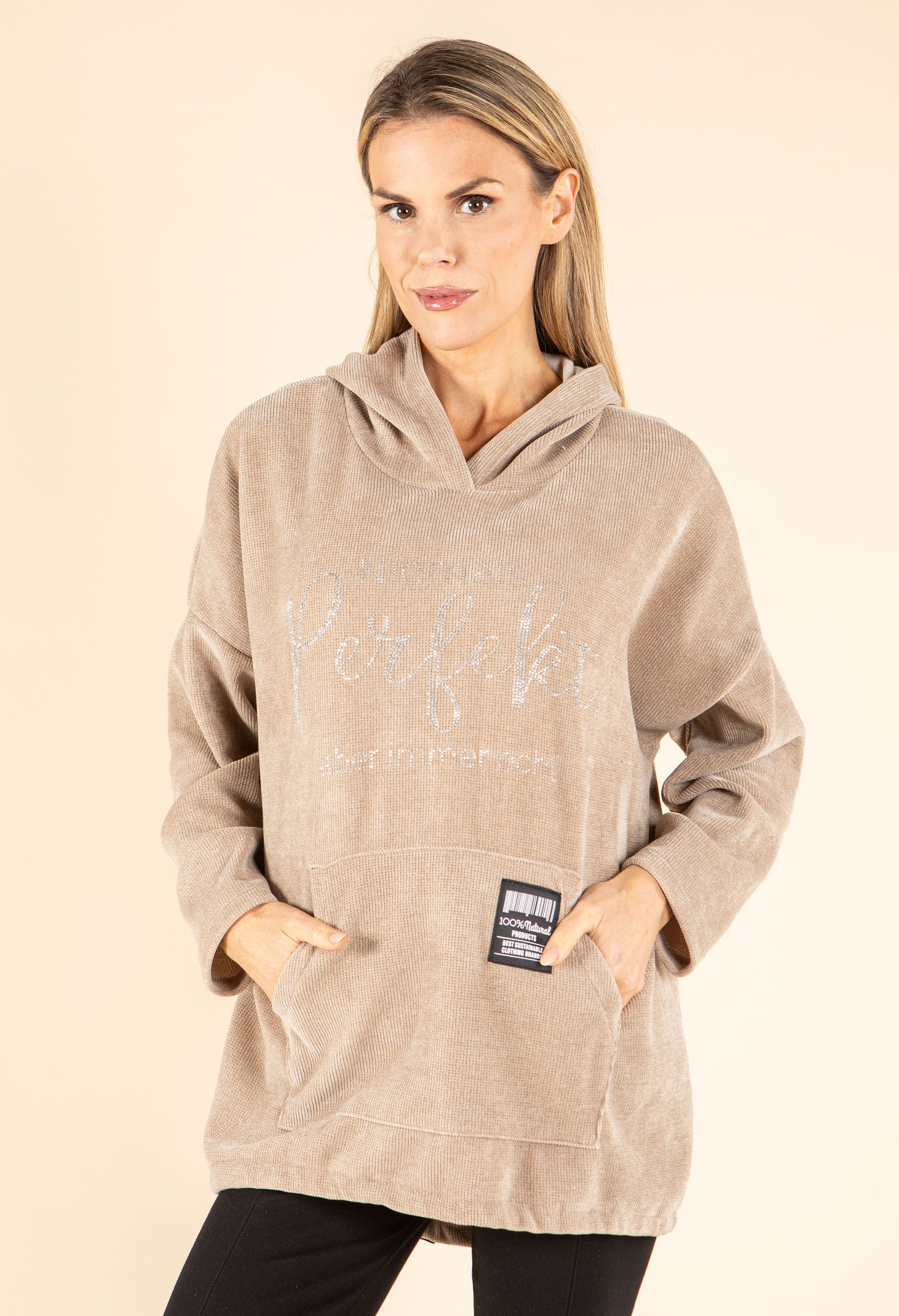 Woman wearing a beige hoodie with text on a beige background