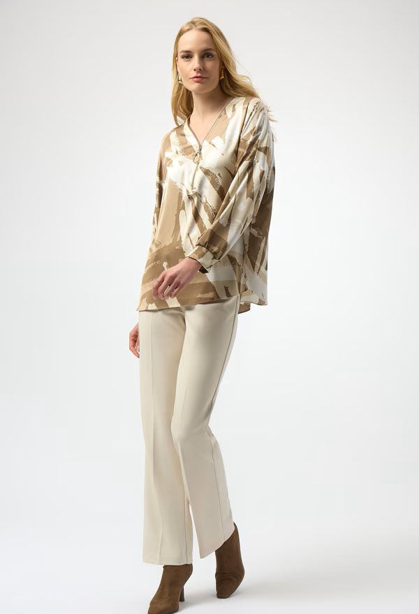 Woman wearing a patterned blouse and white pants on a white background