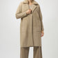 Woman wearing a beige coat and pants on a white background