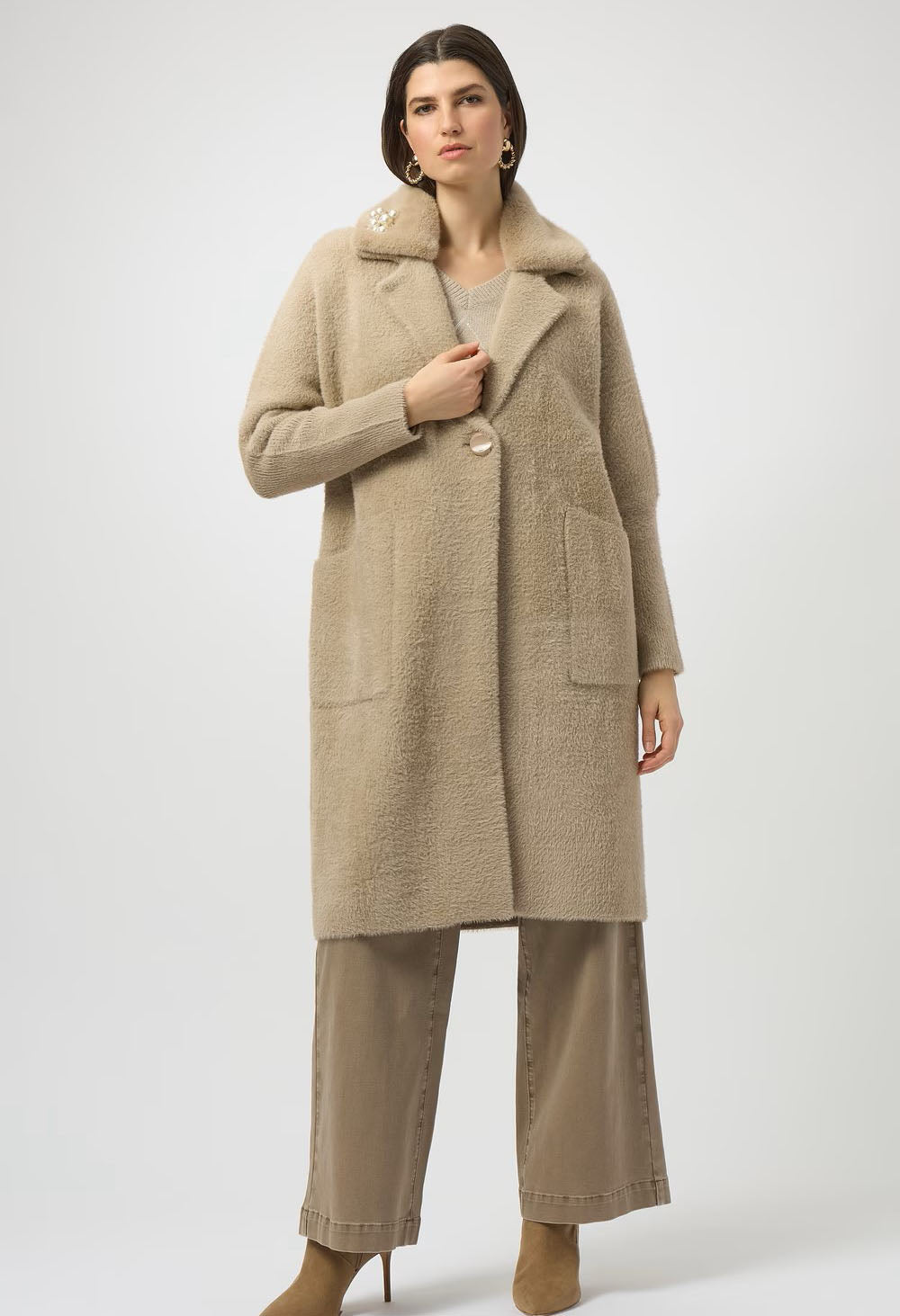 Woman wearing a beige coat and pants on a white background