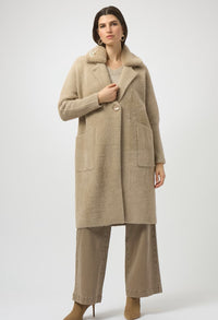 Woman wearing a beige coat and pants on a white background