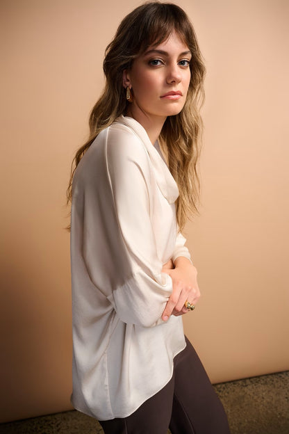 Woman wearing a white blouse against a beige background