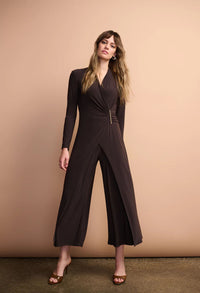 Woman wearing a black jumpsuit against a beige background