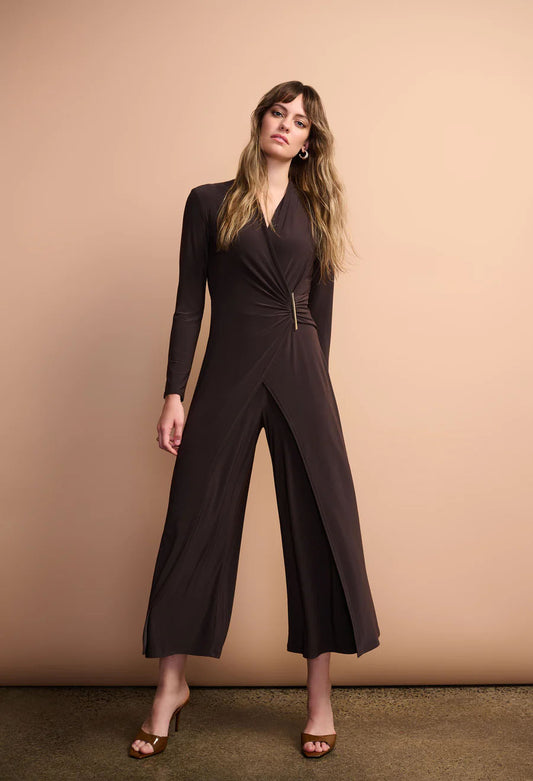 Woman wearing a black jumpsuit against a beige background