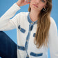 Woman wearing a white cardigan with blue denim accents against a blue background