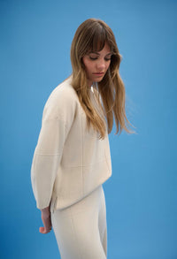 Woman wearing a white suit against a blue background