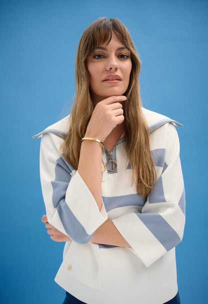 Woman wearing a white and blue striped sweater against a blue background