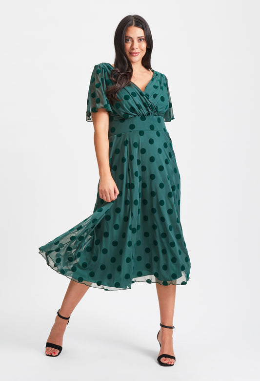 Woman wearing a green polka dot dress on a white background