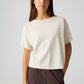 Woman wearing a white top and brown pants on a light gray background