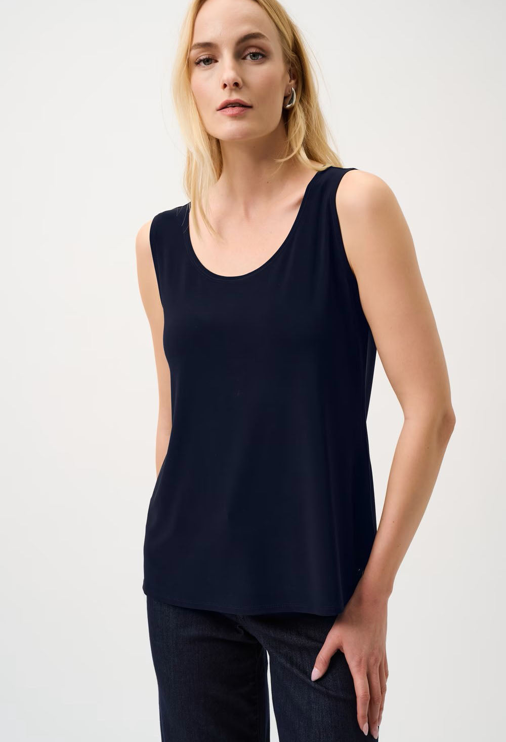 Woman wearing a navy sleeveless top against a white background