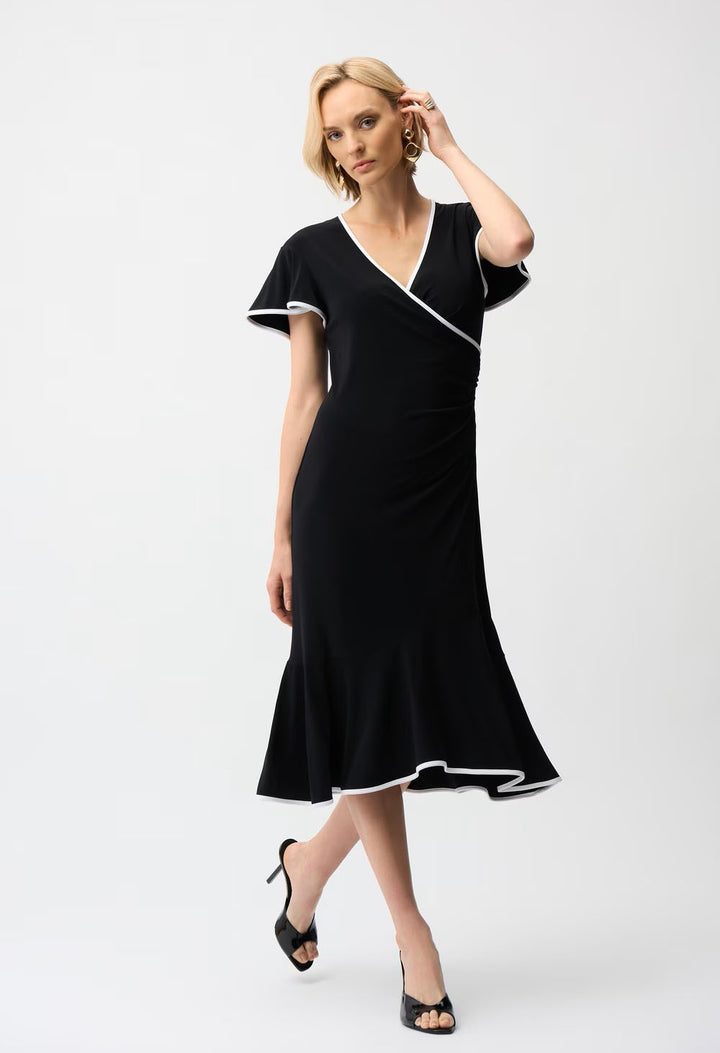 Woman wearing a black dress with white trim on a white background